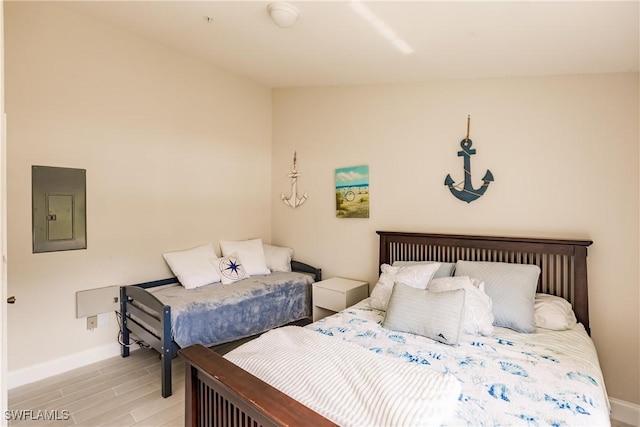 bedroom with electric panel and light wood-type flooring