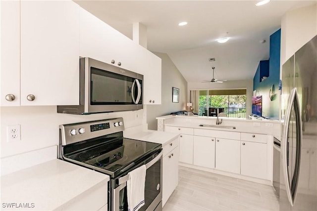 kitchen with sink, white cabinetry, vaulted ceiling, appliances with stainless steel finishes, and ceiling fan