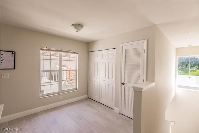 unfurnished bedroom featuring multiple closets and light wood-type flooring