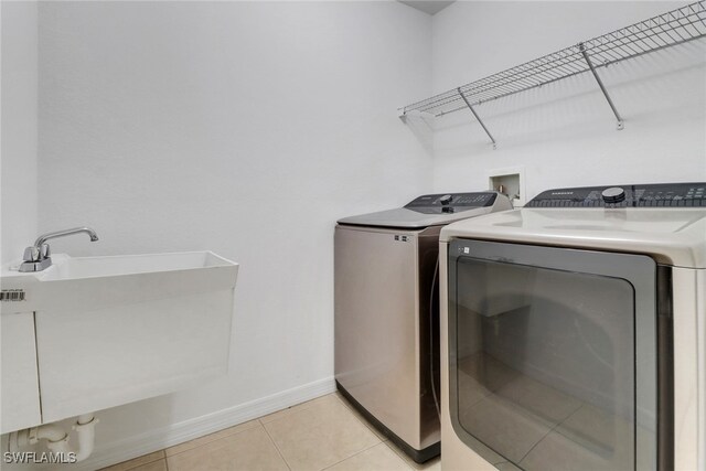 clothes washing area with sink, light tile patterned floors, and independent washer and dryer