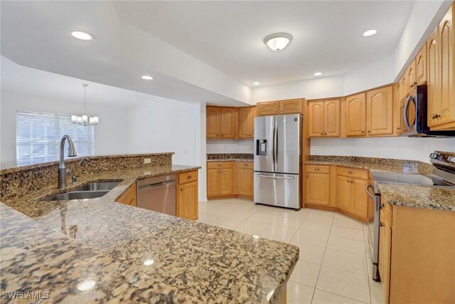 kitchen featuring appliances with stainless steel finishes, pendant lighting, sink, light tile patterned floors, and light stone countertops