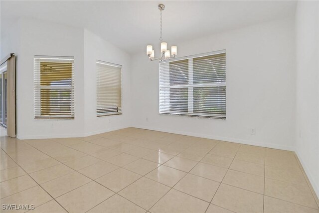 spare room with an inviting chandelier and light tile patterned flooring