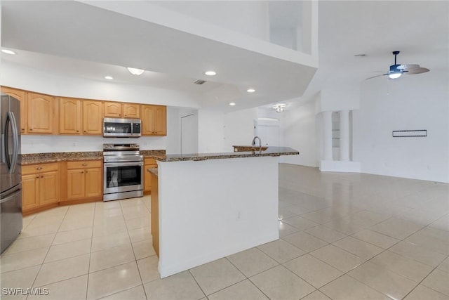 kitchen with stainless steel appliances, dark stone countertops, and light tile patterned flooring