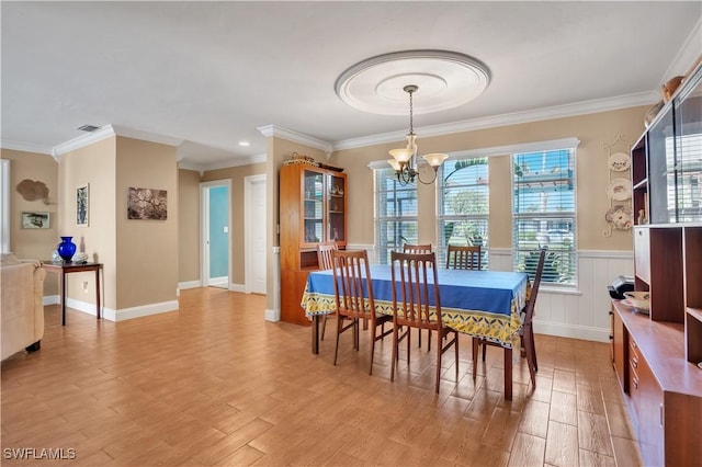 dining area with crown molding, light hardwood / wood-style floors, and a notable chandelier