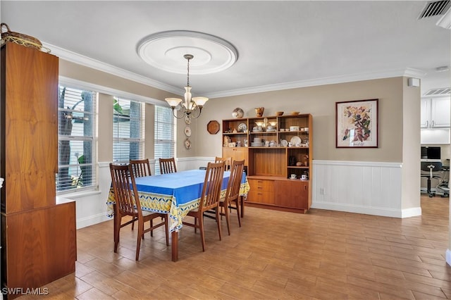 dining area featuring light hardwood / wood-style flooring, an inviting chandelier, a wealth of natural light, and crown molding