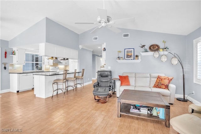 living room featuring ceiling fan, sink, vaulted ceiling, and light wood-type flooring