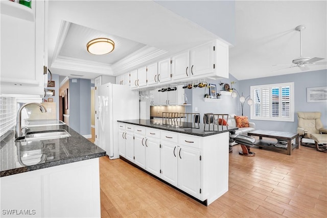 kitchen with dark stone counters, sink, ceiling fan, white cabinetry, and kitchen peninsula