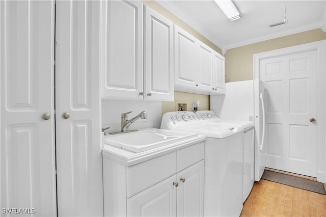 clothes washing area with cabinets, sink, light hardwood / wood-style flooring, washing machine and dryer, and ornamental molding