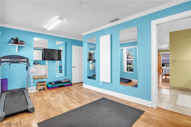 exercise room with light hardwood / wood-style floors and ornamental molding