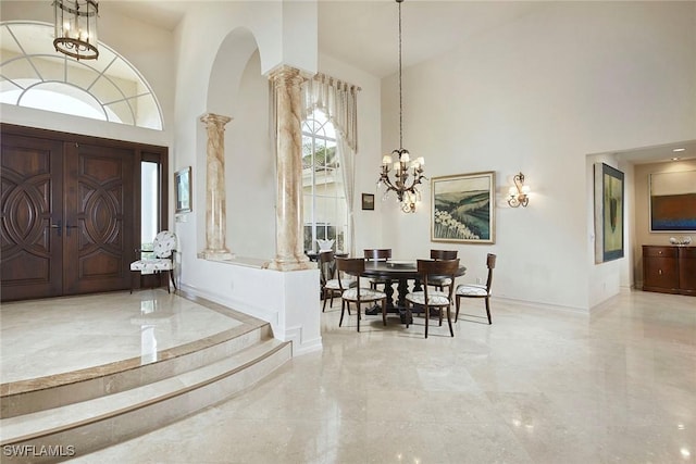 entrance foyer with a towering ceiling, an inviting chandelier, and ornate columns