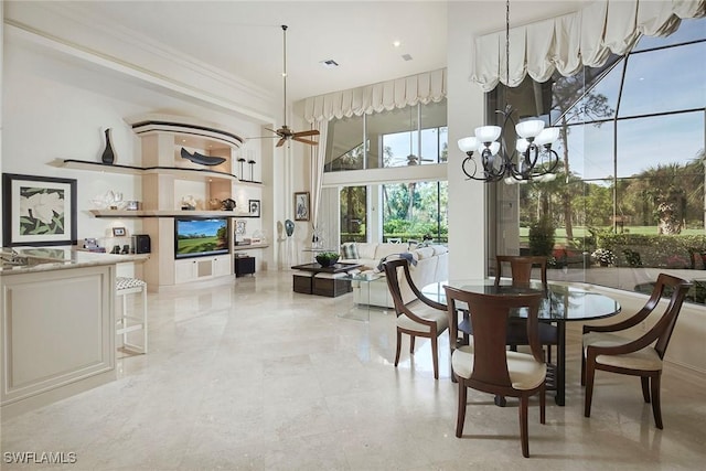 dining space with crown molding, a towering ceiling, and ceiling fan with notable chandelier