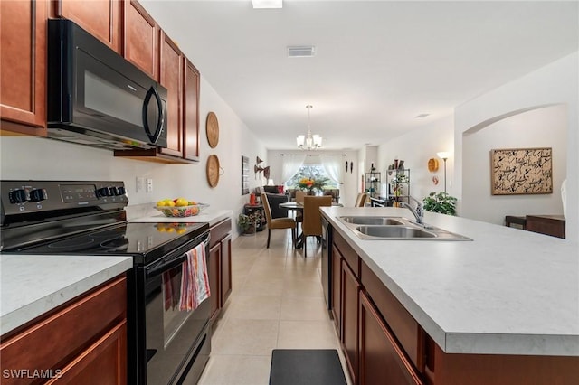 kitchen with an inviting chandelier, black appliances, sink, light tile patterned floors, and an island with sink