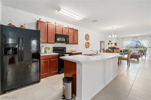 kitchen with a kitchen island with sink, black appliances, sink, hanging light fixtures, and a notable chandelier