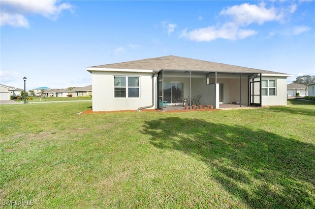 rear view of house with a lawn and glass enclosure