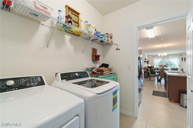 clothes washing area featuring separate washer and dryer, sink, light tile patterned floors, and an inviting chandelier