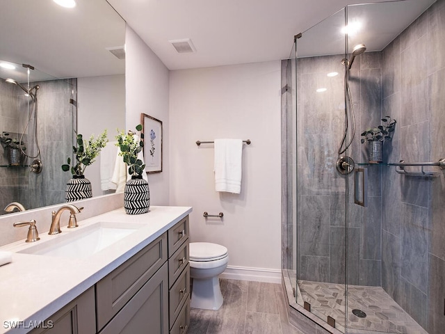 bathroom featuring vanity, a shower with shower door, and toilet