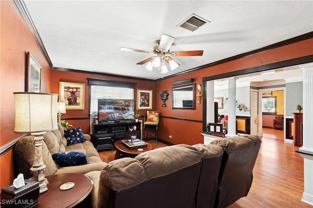 cinema room featuring crown molding, ornate columns, ceiling fan, and light wood-type flooring