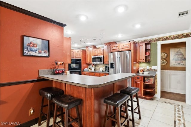 kitchen with appliances with stainless steel finishes, backsplash, ornamental molding, a kitchen bar, and kitchen peninsula