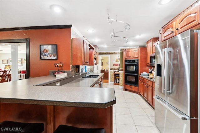 kitchen with sink, appliances with stainless steel finishes, ornamental molding, light tile patterned flooring, and kitchen peninsula