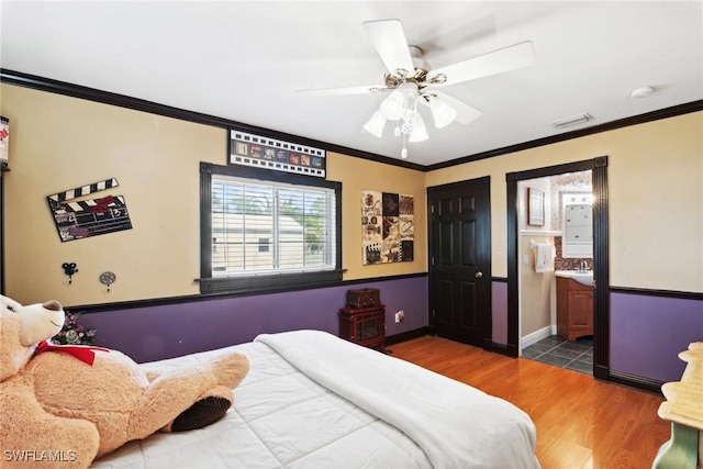 bedroom with ornamental molding, dark wood-type flooring, ensuite bathroom, and ceiling fan