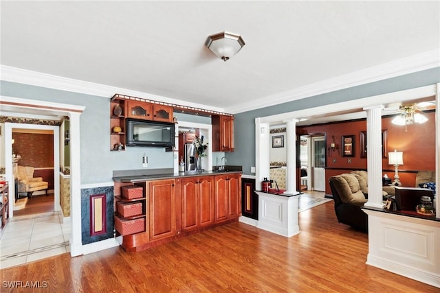 kitchen with decorative columns, ornamental molding, sink, and light hardwood / wood-style flooring