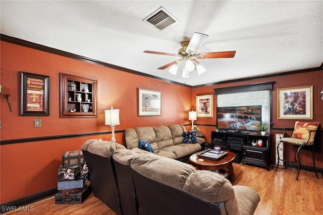 living room with ceiling fan, ornamental molding, and light wood-type flooring