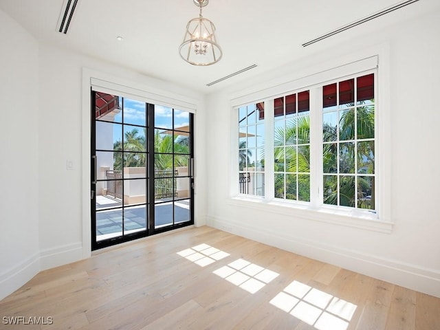 unfurnished room with a chandelier and light hardwood / wood-style floors