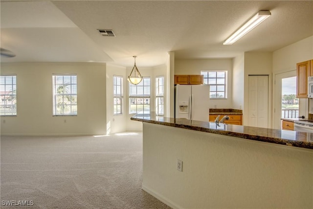 kitchen with white appliances, decorative light fixtures, and light carpet