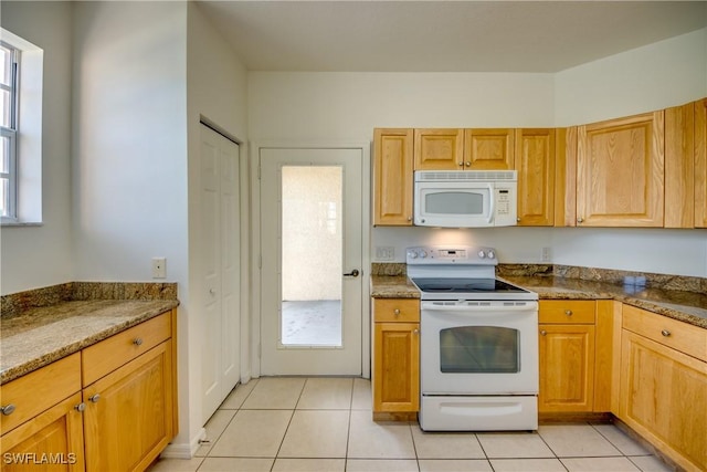 kitchen featuring white appliances, dark stone countertops, and light tile patterned floors