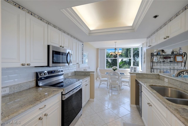 kitchen with white cabinetry, sink, pendant lighting, a tray ceiling, and appliances with stainless steel finishes