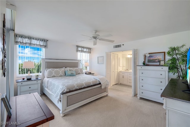 bedroom featuring ceiling fan, ensuite bathroom, and light carpet