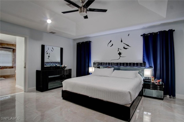 bedroom with a tray ceiling, ceiling fan, and ensuite bathroom