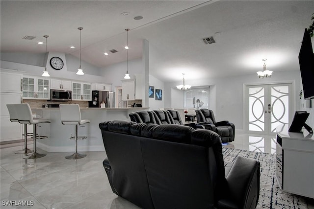 living room featuring french doors, a chandelier, and lofted ceiling