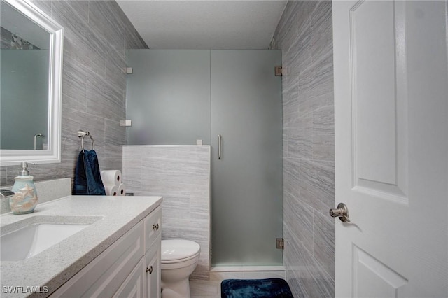 bathroom with vanity, toilet, tile walls, and walk in shower