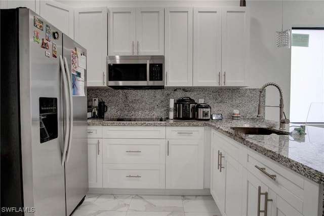 kitchen with light stone countertops, sink, backsplash, white cabinets, and appliances with stainless steel finishes