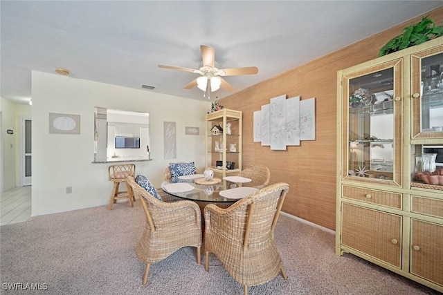 dining room with ceiling fan, light carpet, and wooden walls