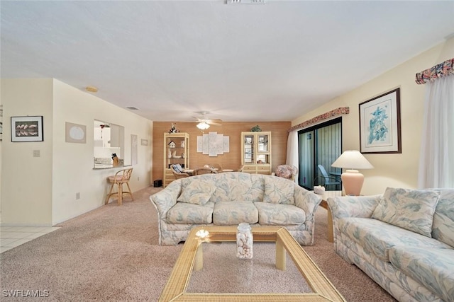 carpeted living room with ceiling fan and wooden walls