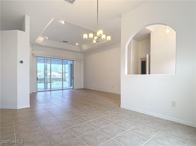 tiled spare room with an inviting chandelier and a tray ceiling