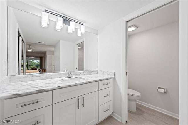 bathroom featuring ceiling fan, hardwood / wood-style flooring, vanity, and toilet