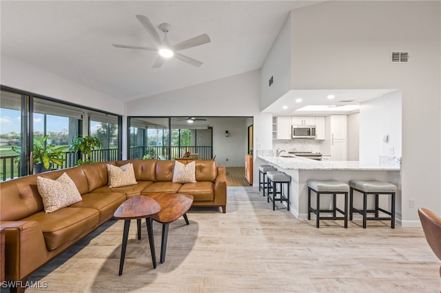 living room with ceiling fan, sink, and high vaulted ceiling