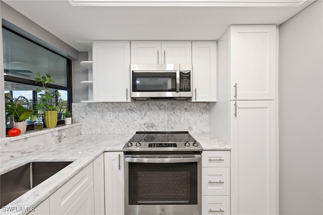 kitchen featuring decorative backsplash, light stone countertops, white cabinetry, and stainless steel appliances