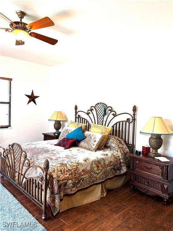 bedroom with dark hardwood / wood-style flooring and ceiling fan