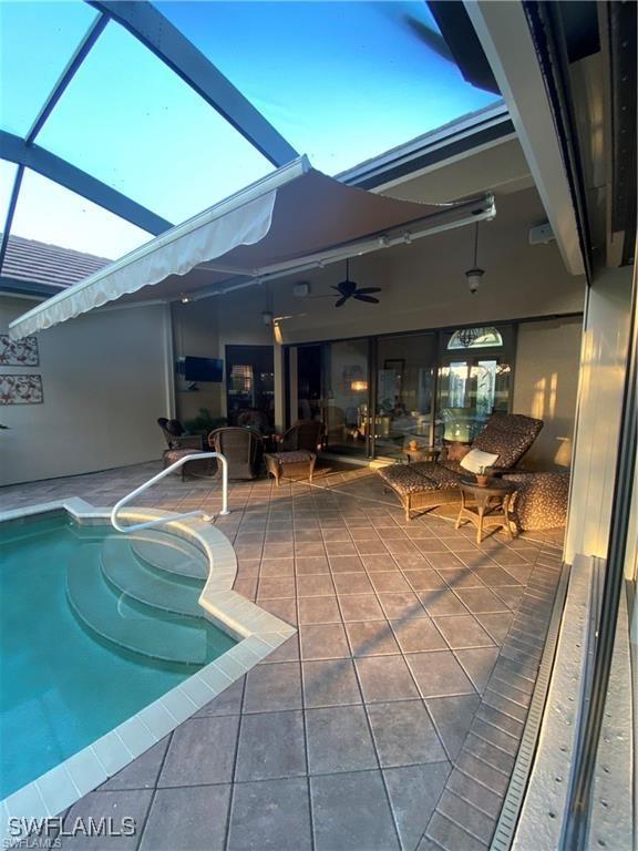 pool at dusk featuring a lanai and a patio