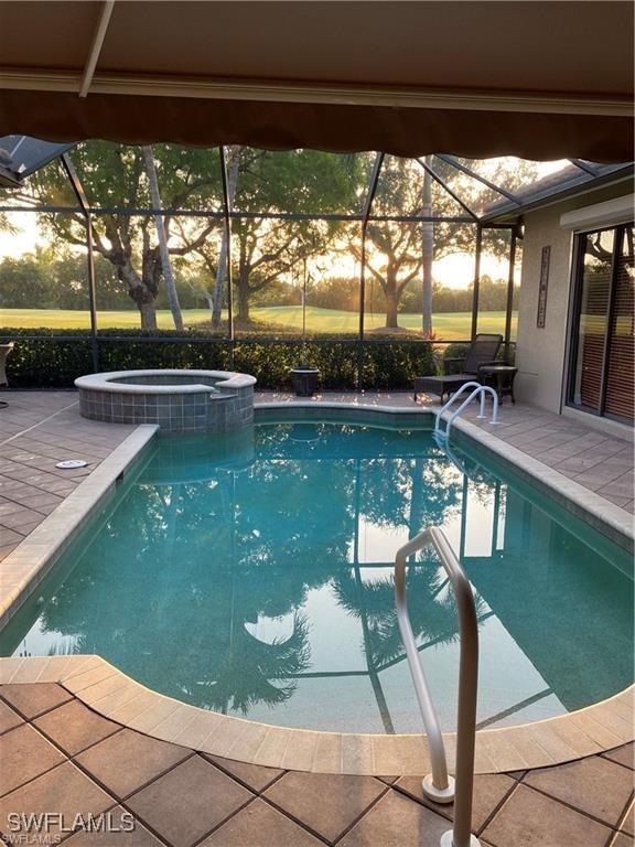 view of swimming pool featuring an in ground hot tub, a patio, and a lanai