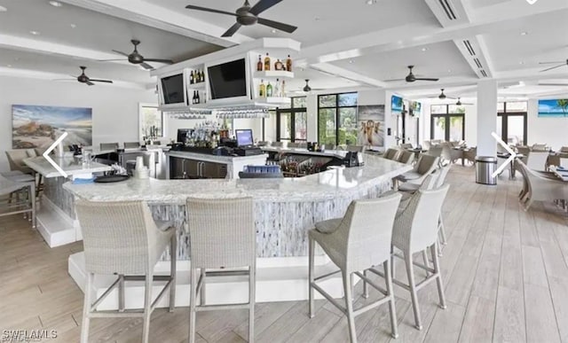 kitchen featuring light stone counters, a kitchen bar, and light hardwood / wood-style flooring