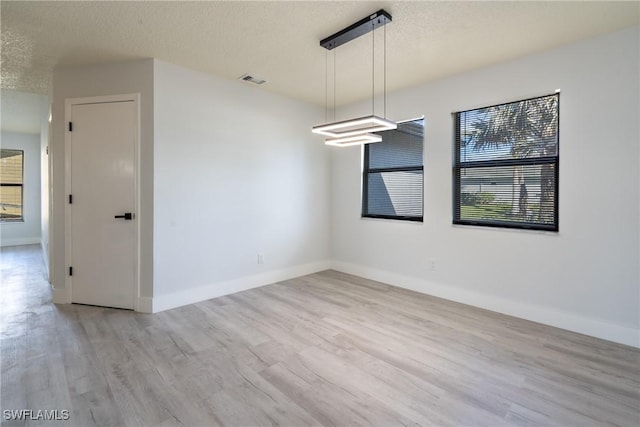 empty room with a textured ceiling and light wood-type flooring