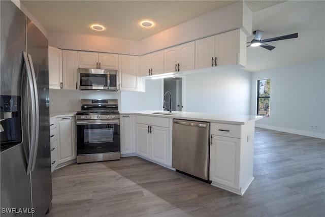 kitchen with sink, white cabinetry, light hardwood / wood-style flooring, kitchen peninsula, and stainless steel appliances