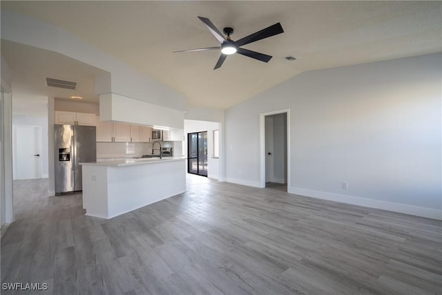 kitchen featuring appliances with stainless steel finishes, lofted ceiling, sink, white cabinets, and light hardwood / wood-style floors