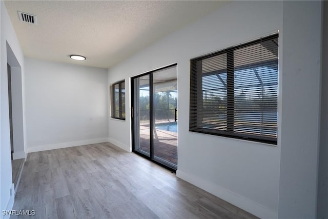 unfurnished room featuring light wood-type flooring and a textured ceiling