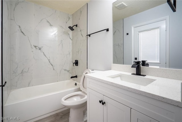 full bathroom with tiled shower / bath combo, vanity, wood-type flooring, a textured ceiling, and toilet